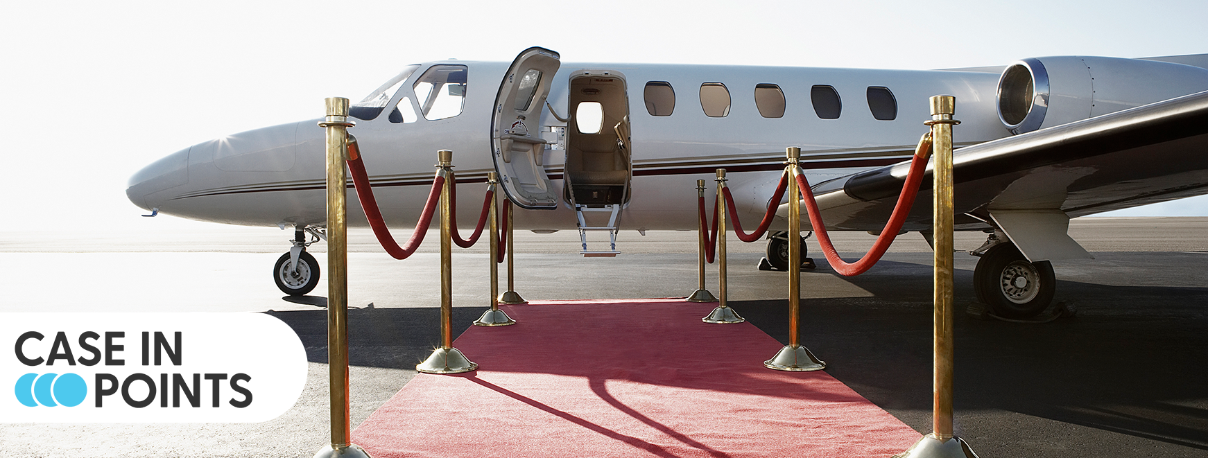 Case in Points. Airplane with red carpet and roping leading to cabin entry. 